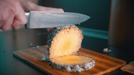 Cutting a pineapple in pieces with a knife