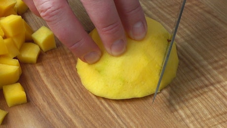Cutting mango on a board, close up