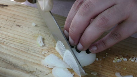 Cutting onion into slices on a board.
