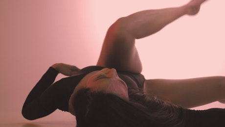 Dancer moving her body lying on the floor.