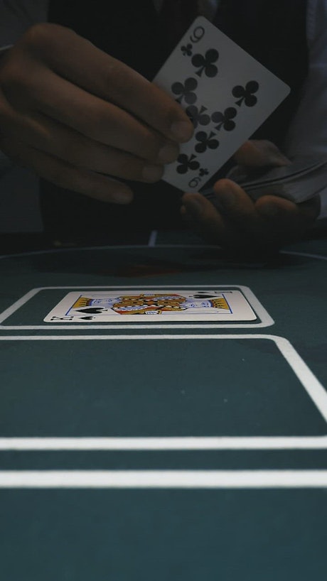 Dealer placing poker cards on a gaming table.