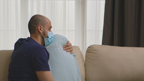 Depressed man hugs pillow in coronavirus quarantine.
