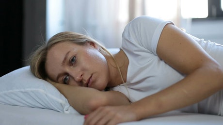 Depressed woman laying in bed.