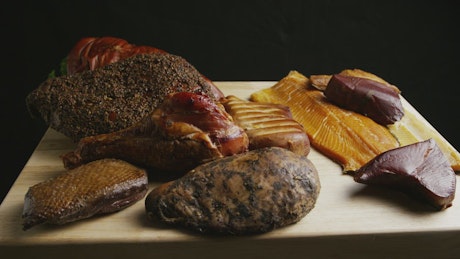 Different types of meat rotating on a wooden board