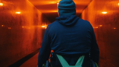 Disabled man in a wheelchair crossing an underpass tunnel.