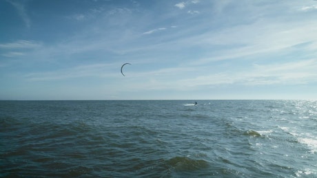 Distance shot of a kitesurfer followint the camera.