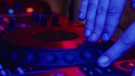 DJ hand mixing music at a nightclub.
