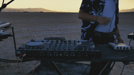 Dj mixing music in the middle of a big desert