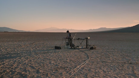 Dj playing music in the middle of a sunny desert.