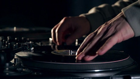 DJ scratching a vinyl on a turntable.