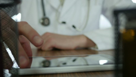 Doctor typing on a tablet in the desk