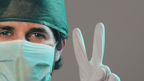 Doctor wearing a mask holding up the peace sign.