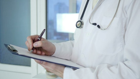 Doctor writing on medical record
