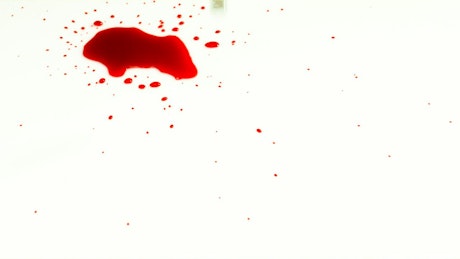 Droplets of blood fall onto white surface.