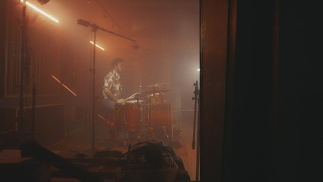 Drummer playing in a studio full of instruments.
