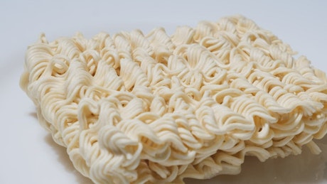 Dry instant noodles on white rotary surface before cooking.
