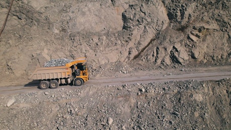Dump truck driving along a road in a large coal mine.