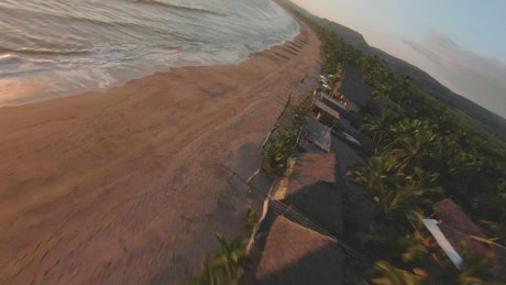 Dynamic drone tour of a beach at sunset.
