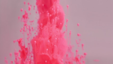 Dynamic movement of pink ink clouds in water.