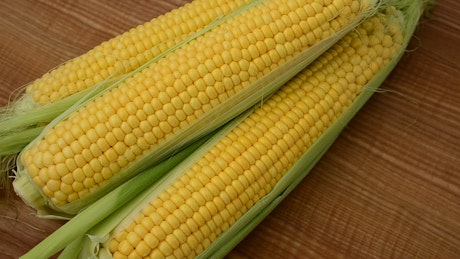 Ears of corn, turning on a wooden surface