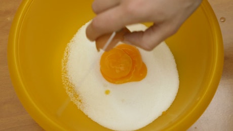 Egg yolk being placed into a bowl while making a cake.