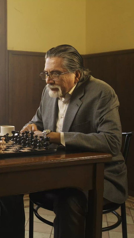 Elderly man in a game of chess with an opponent.