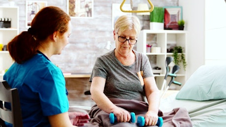 Elderly woman in physical therapy with nurse.
