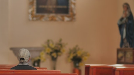 Elderly woman sitting on a pew in a church