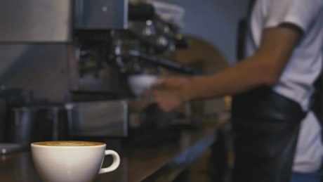 Employee serving a cup of coffee from a machine