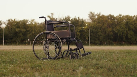 Empty wheelchair in a grassy field.