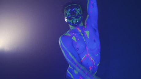 Energetic dance of a boy with a neon mask.