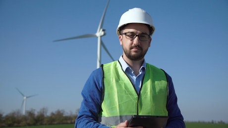 Engineer standing on a wind turbines field.