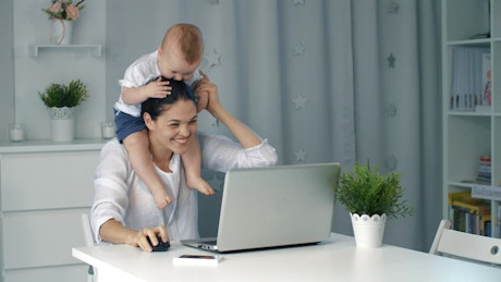 Enterprising mom plays with her baby while working.