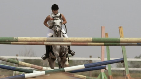 Equestrian jumping a horse over obstacles.