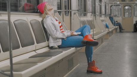 疲惫的年轻女子坐在地铁里听音乐
