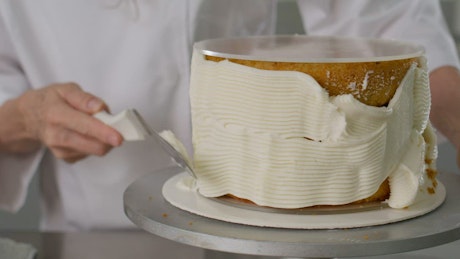 Expert pastry chef covering a cake with icing.