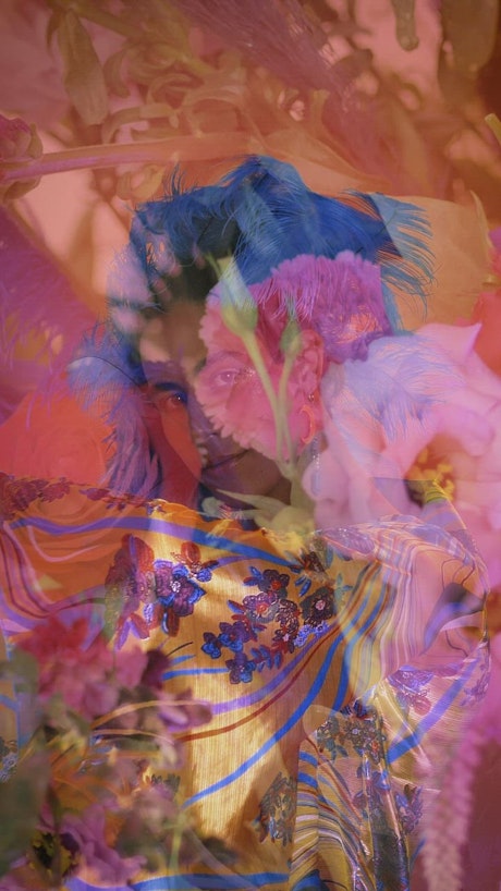 Extravagant gay boy in abstract video with flowers.