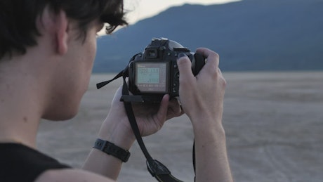 Face of a boy taking pictures in a desert.