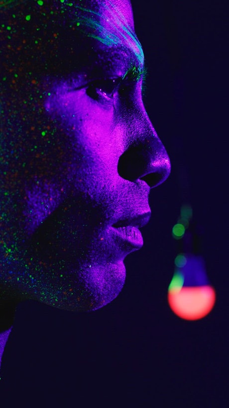 Face of a man stained with phosphorescent colors.