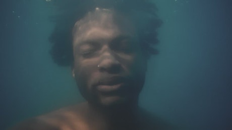 Face of a man submerged under water.