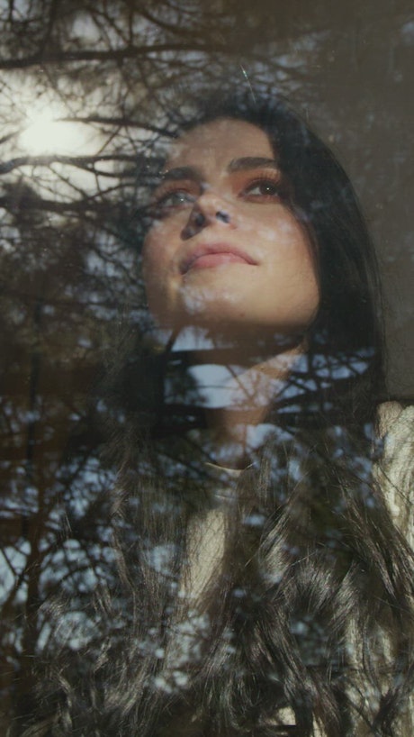 Face of a woman looking through a window.