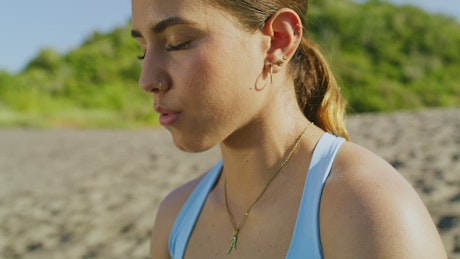 Face of a woman meditating on a sunny beach.