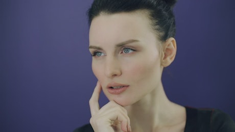 Face of a young pensive woman on a purple background