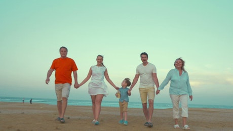 Family holding hands at the beach.