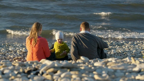 Family sitting on a pebble beach