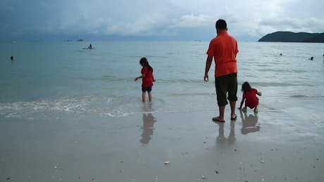 Family standing in shallow waves