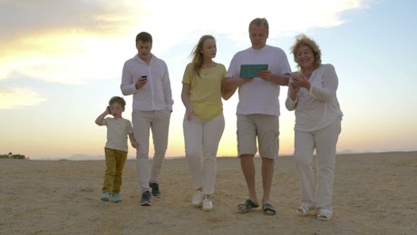 Family walking along the beach with a tablet.