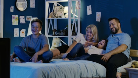 Family watching the TV in the bedroom.