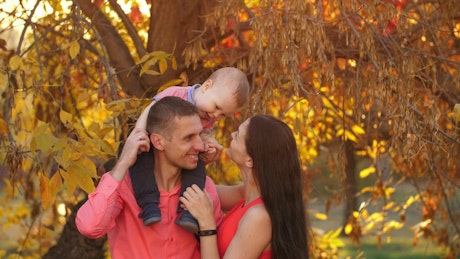 Father and mother with their baby in autumn nature.