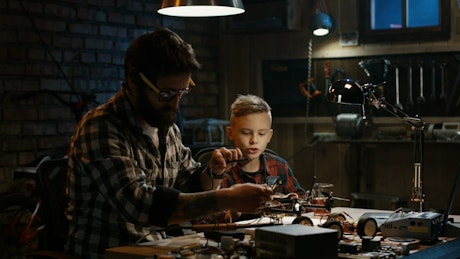 Father and son repairing a drone in the garage.